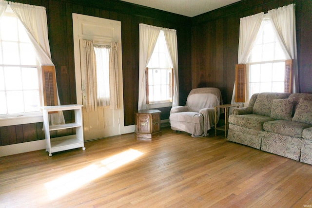 sitting room with a healthy amount of sunlight, light hardwood / wood-style floors, and wood walls