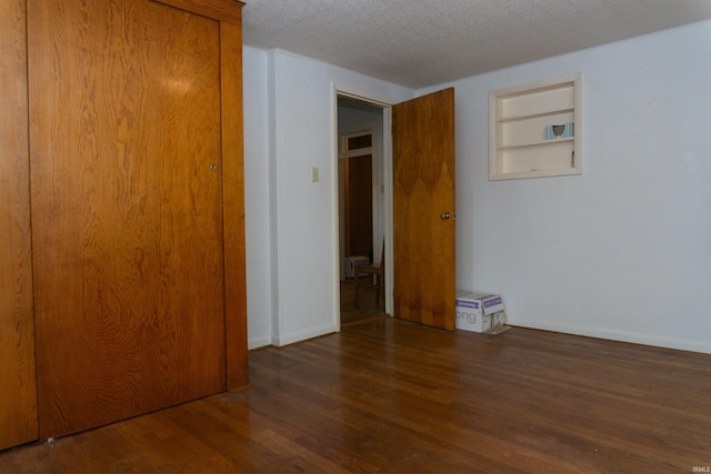 unfurnished bedroom featuring a textured ceiling, a closet, and dark wood-type flooring