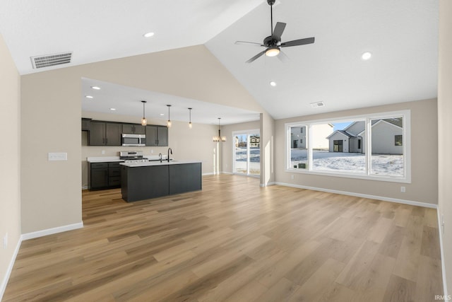 unfurnished living room featuring high vaulted ceiling, sink, ceiling fan with notable chandelier, and light hardwood / wood-style flooring