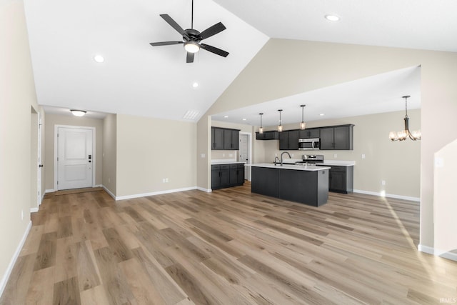 unfurnished living room with hardwood / wood-style flooring, sink, ceiling fan with notable chandelier, and high vaulted ceiling