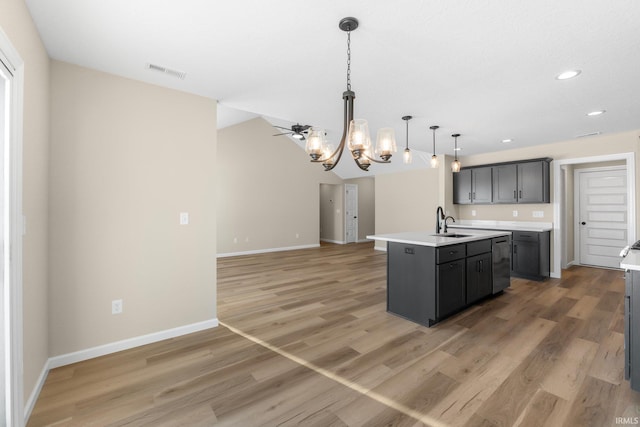 kitchen with wood-type flooring, a kitchen island with sink, sink, and decorative light fixtures