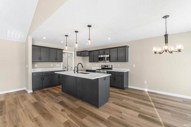 kitchen with stainless steel appliances, an island with sink, sink, and dark hardwood / wood-style floors