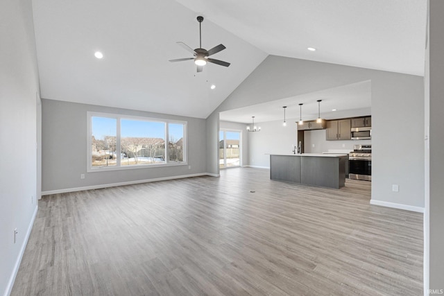 602 Zion Hill Rd, Ligonier, IN 46767 - unfurnished living room with ceiling fan with notable chandelier, high vaulted ceiling, light wood-style floors, and baseboards