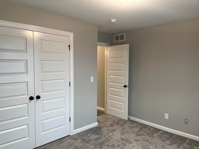 unfurnished bedroom with a textured ceiling, carpet flooring, and a closet