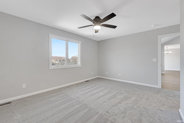 spare room with ceiling fan with notable chandelier and carpet floors