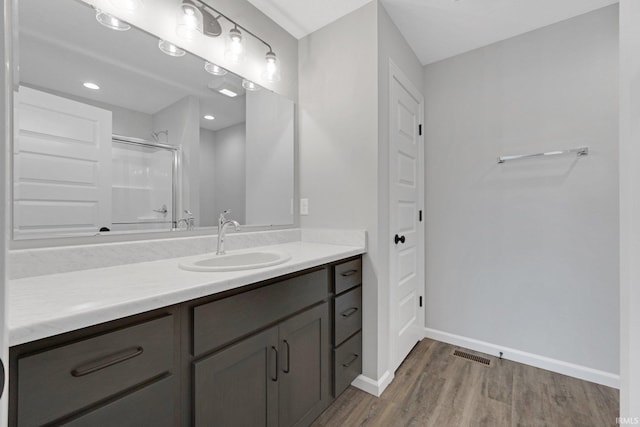 bathroom featuring hardwood / wood-style flooring, a shower with shower door, and vanity