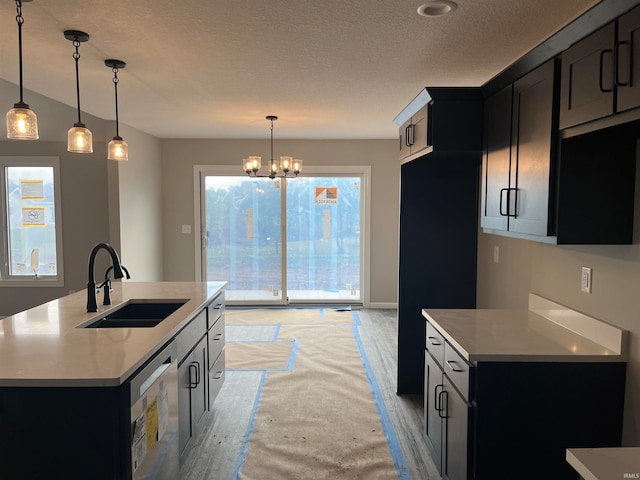 kitchen featuring sink, stainless steel dishwasher, pendant lighting, and an island with sink