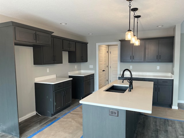 kitchen featuring sink, a kitchen island with sink, dark hardwood / wood-style floors, and decorative light fixtures