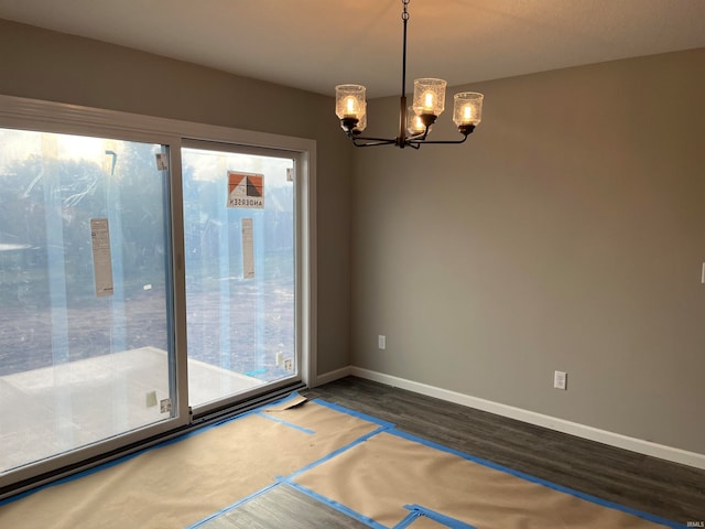 empty room featuring dark hardwood / wood-style flooring and a notable chandelier