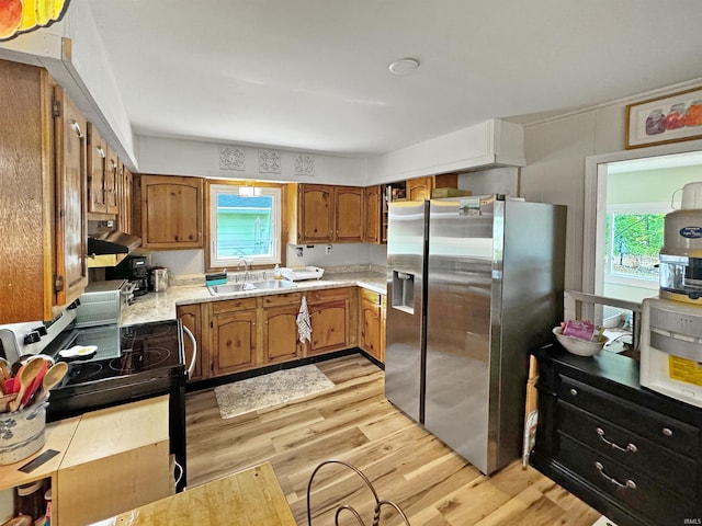 kitchen with a healthy amount of sunlight, sink, stainless steel refrigerator with ice dispenser, and light hardwood / wood-style flooring