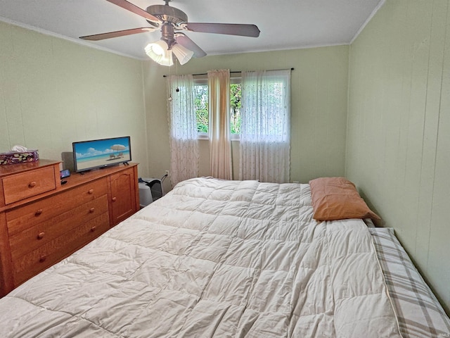 bedroom with ceiling fan, crown molding, and wood walls