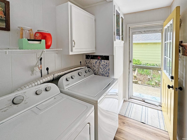 clothes washing area with a healthy amount of sunlight, cabinets, light wood-type flooring, and separate washer and dryer