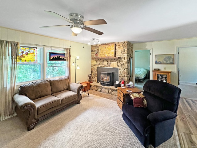 living room featuring a wood stove, ceiling fan, and light hardwood / wood-style flooring