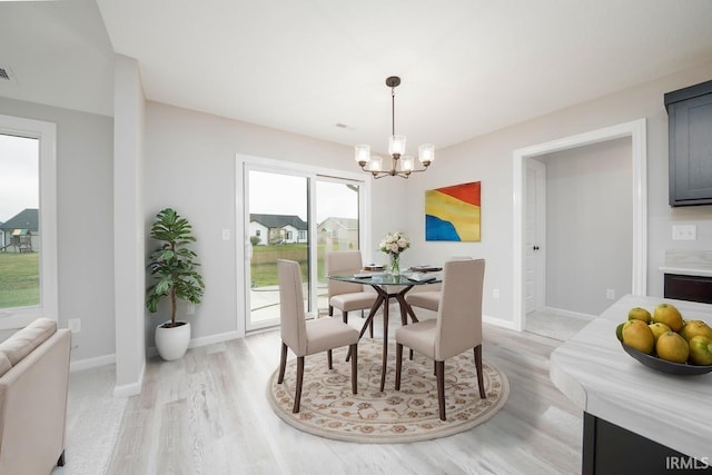 dining area with light wood-type flooring and a chandelier