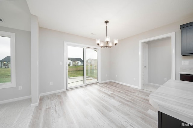 unfurnished dining area with a notable chandelier and light wood-type flooring