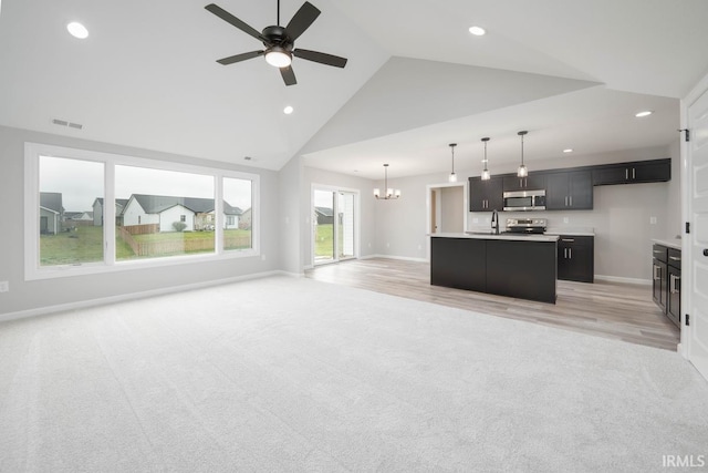 kitchen with a center island with sink, light hardwood / wood-style floors, ceiling fan with notable chandelier, and stainless steel appliances