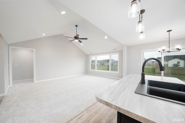 kitchen with ceiling fan with notable chandelier, vaulted ceiling, plenty of natural light, and sink