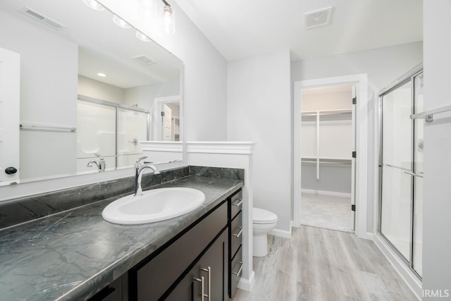 bathroom with vanity, toilet, a shower with door, and hardwood / wood-style flooring