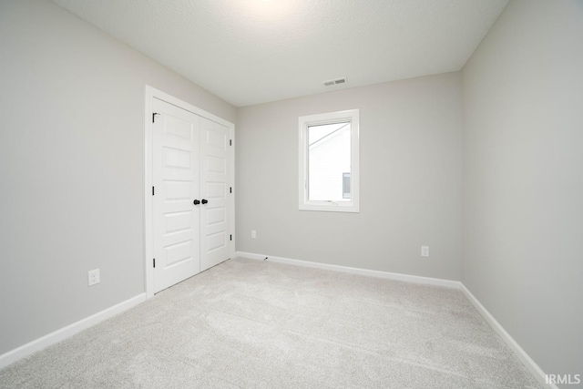 unfurnished room with a textured ceiling and light carpet