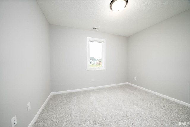 carpeted empty room featuring a textured ceiling