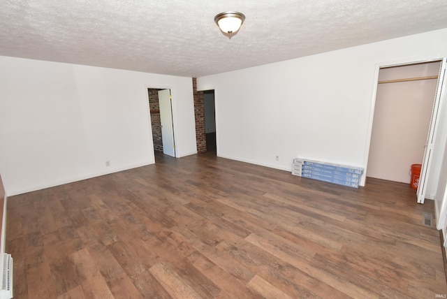 unfurnished bedroom with a textured ceiling and dark wood-type flooring