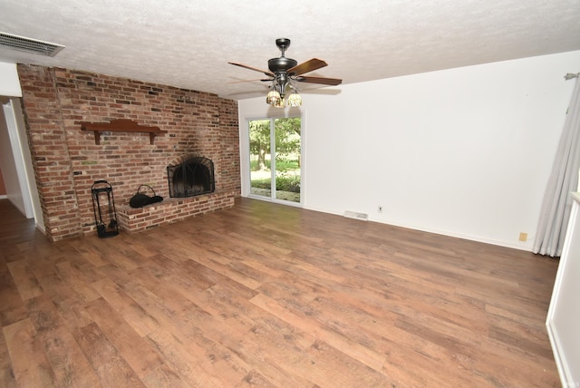 unfurnished living room with ceiling fan, a textured ceiling, a fireplace, and wood-type flooring