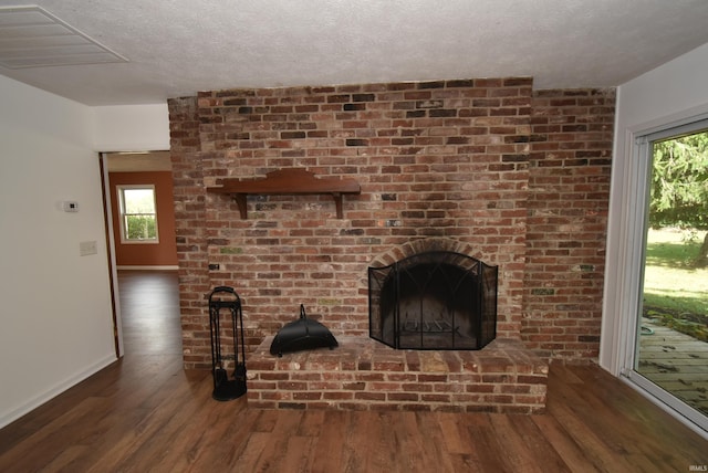 unfurnished living room with a brick fireplace, a wealth of natural light, and dark hardwood / wood-style flooring