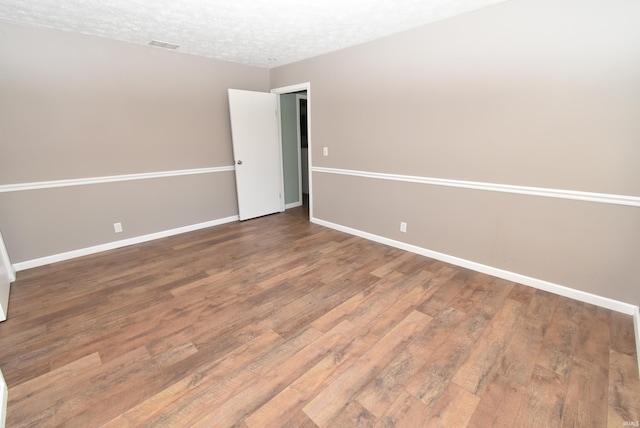 unfurnished room featuring a textured ceiling and hardwood / wood-style flooring