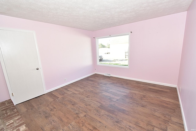 spare room featuring a textured ceiling and dark hardwood / wood-style floors