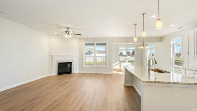 kitchen with sink, ceiling fan with notable chandelier, light hardwood / wood-style floors, and decorative light fixtures