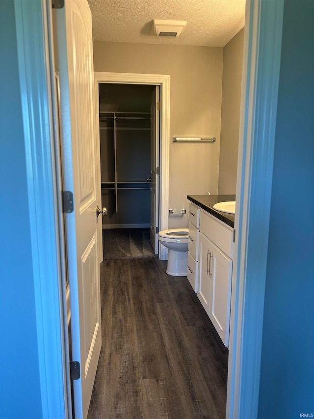 bathroom featuring a textured ceiling, hardwood / wood-style floors, vanity, and toilet