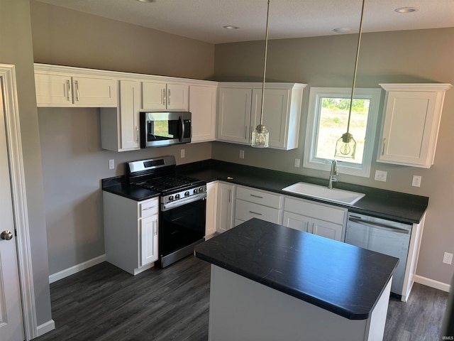 kitchen with white cabinetry, vaulted ceiling, pendant lighting, stainless steel appliances, and sink