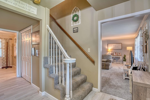 stairs with a fireplace, ornamental molding, and hardwood / wood-style floors