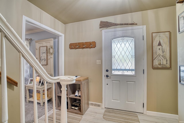 foyer featuring light wood-type flooring and ornamental molding