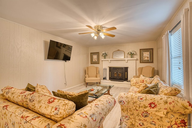 living room with ceiling fan, hardwood / wood-style flooring, wooden walls, and a brick fireplace