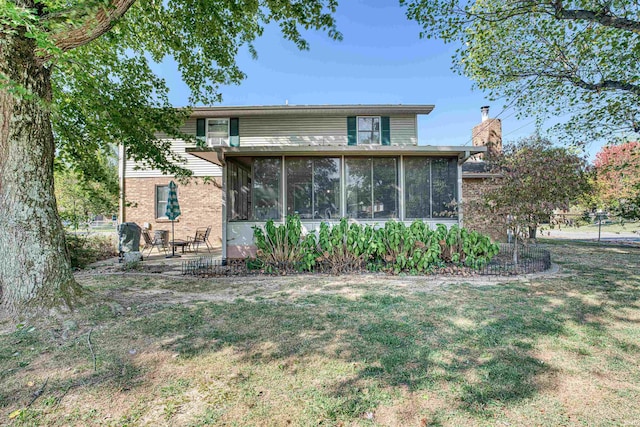 rear view of property featuring a sunroom and a yard