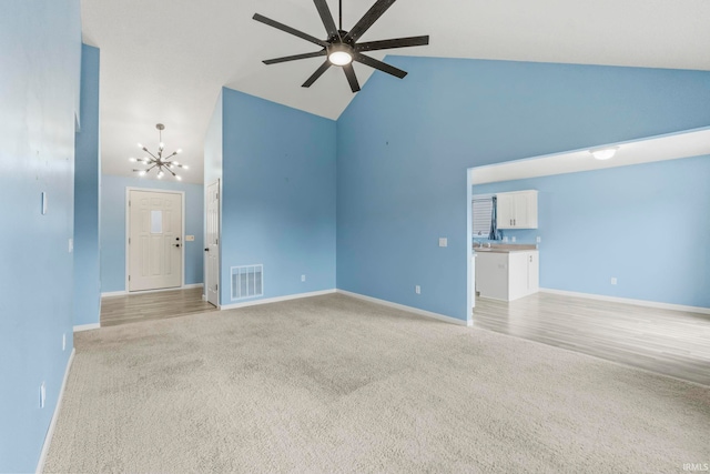 unfurnished room featuring ceiling fan with notable chandelier, light carpet, and high vaulted ceiling