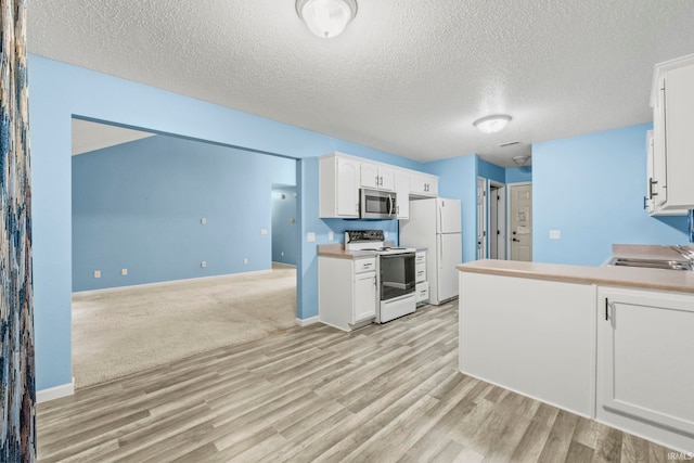 kitchen with white cabinets, a textured ceiling, light hardwood / wood-style flooring, and white appliances