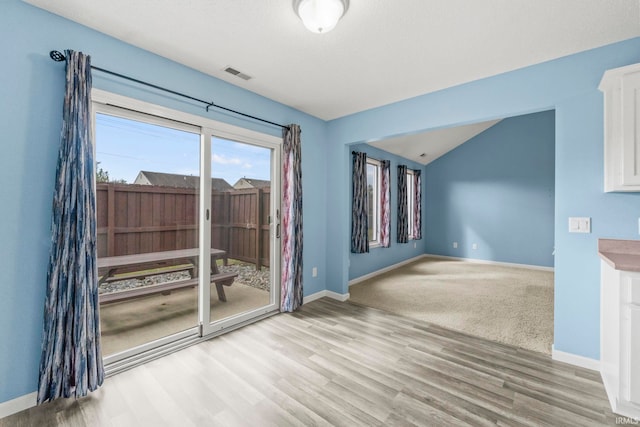 spare room with light wood-type flooring and vaulted ceiling