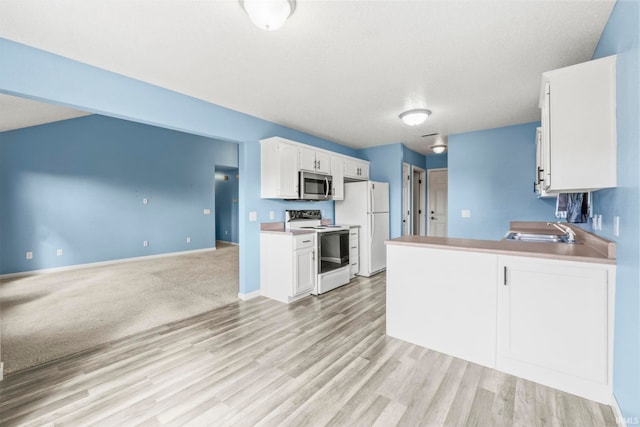 kitchen featuring light wood-type flooring, a textured ceiling, sink, white cabinets, and white appliances