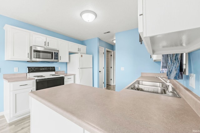 kitchen with sink, kitchen peninsula, white appliances, light hardwood / wood-style flooring, and white cabinetry