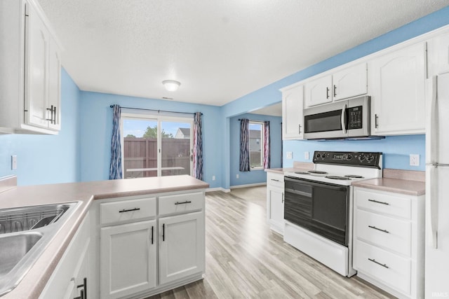 kitchen with white cabinets, a textured ceiling, light wood-type flooring, and white appliances