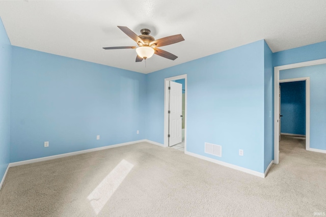 carpeted spare room with ceiling fan