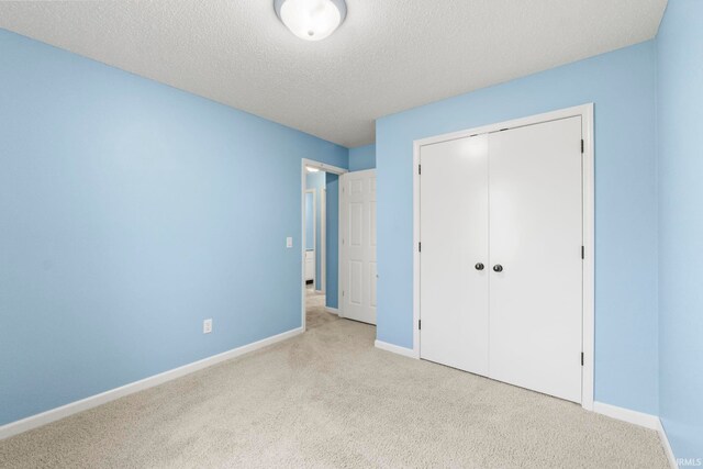 unfurnished bedroom with a textured ceiling, light colored carpet, and a closet