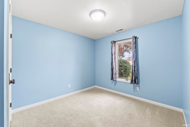 carpeted empty room featuring a textured ceiling