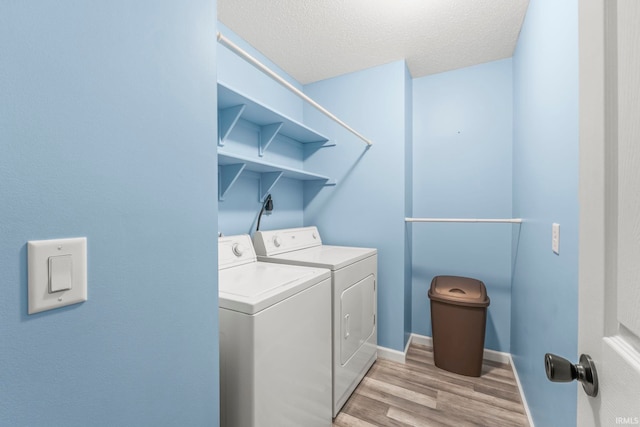 laundry area featuring a textured ceiling, light wood-type flooring, and washing machine and clothes dryer