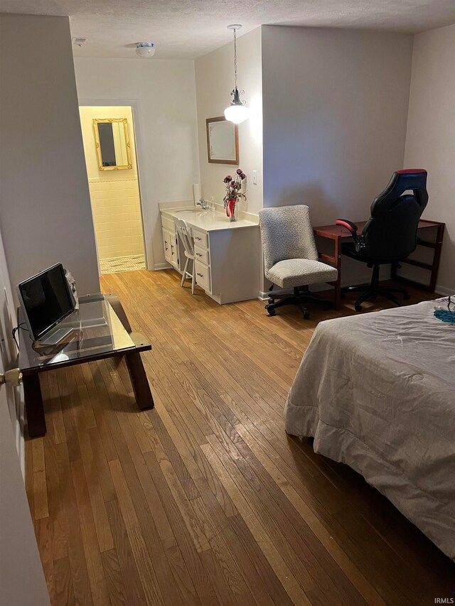 bedroom with sink, a textured ceiling, and light wood-type flooring