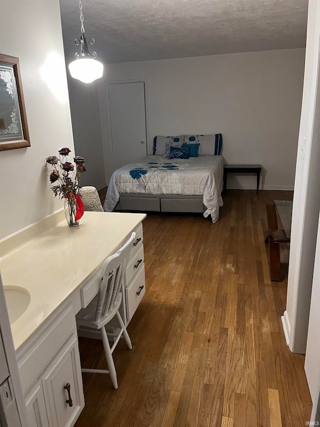 bedroom featuring light hardwood / wood-style floors, a textured ceiling, and built in desk