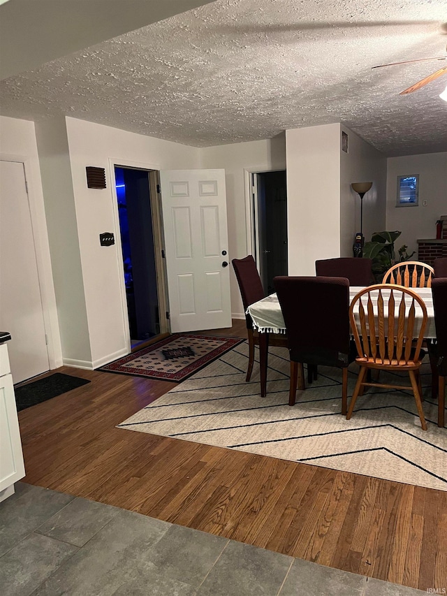 dining space with ceiling fan, dark wood-type flooring, and a textured ceiling