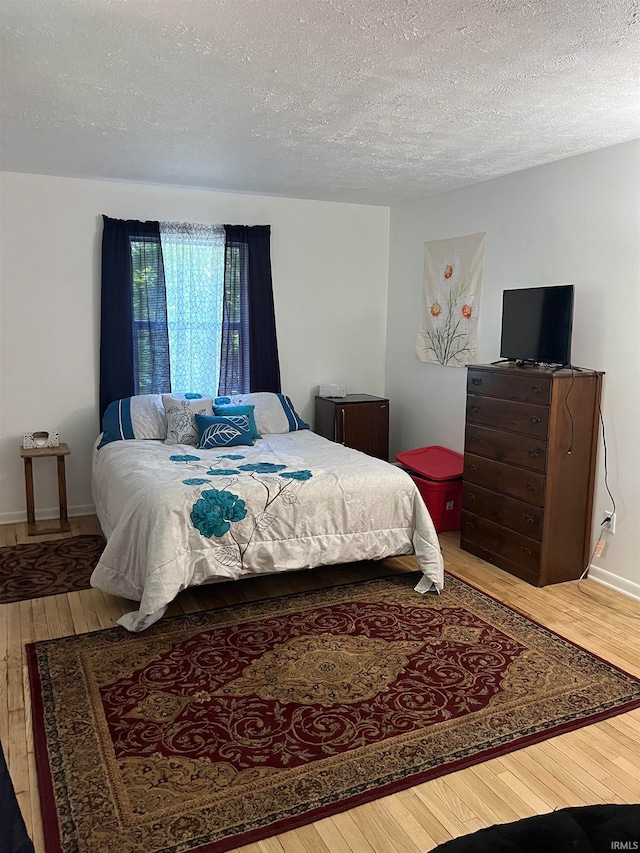 bedroom with a textured ceiling and hardwood / wood-style flooring